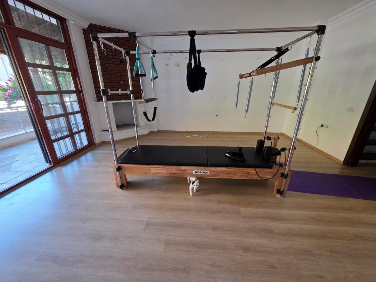 Gün ışığı alan bir odada trapez ve askıları olan ahşap gövdeli Cadillac reformer