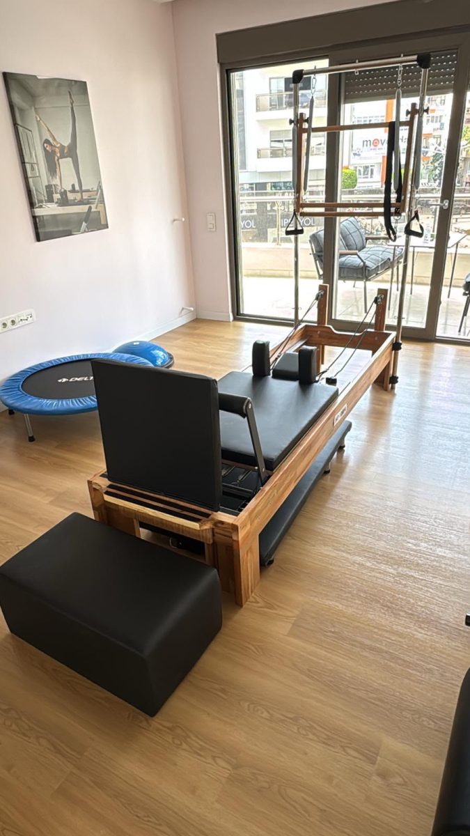 Arka planda denge topu ve mini trampolin bulunan stüdyoda oturma kutulu tower reformer